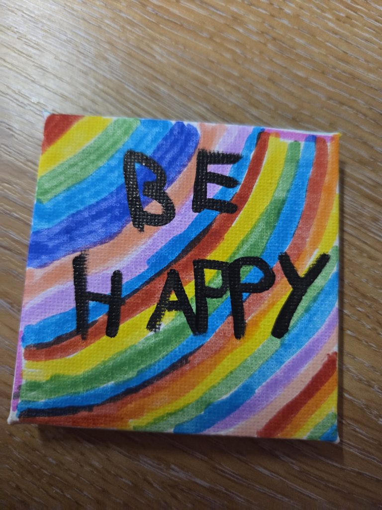 colourful painting saying "be happy"