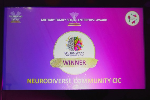 Awards ceremony screen showing NeuroDiverse Community CIC as the winner of the Military Family Social Enterprise Award at the Celebrating Forces Families Awards. The screen has a purple and pink background with the NDC logo in the centre and the word “Winner” displayed underneath.