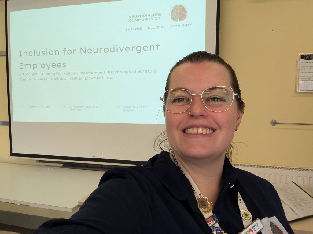 A smiling woman wearing glasses takes a selfie in front of a presentation slide.